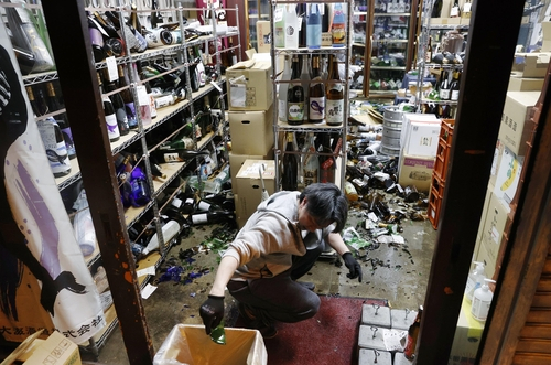 후쿠시마시의 한 주류 매장에서 점장이 지진으로 인해 깨진 술병을 치우고 있다.