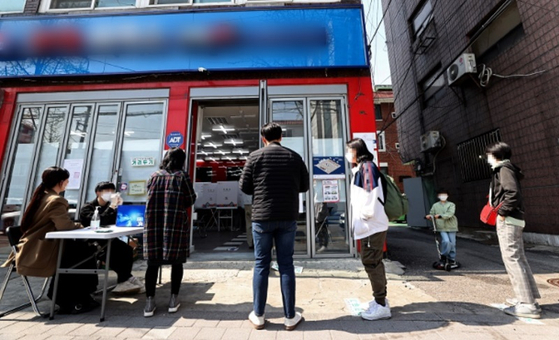 서울의 한 썬팅 업소에 마련된 투표소에서 유권자들이 투표를 위해 줄을 서 있다.〈사진-연합뉴스〉