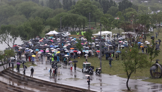 지난 16일 오후 서울 반포한강공원 수상택시 승강장 인근에서 열린 '고 손정민 군을 위한 평화집회'에서 참가자들이 우산을 쓴 채 자리를 지키고 있다. 〈사진=연합뉴스〉