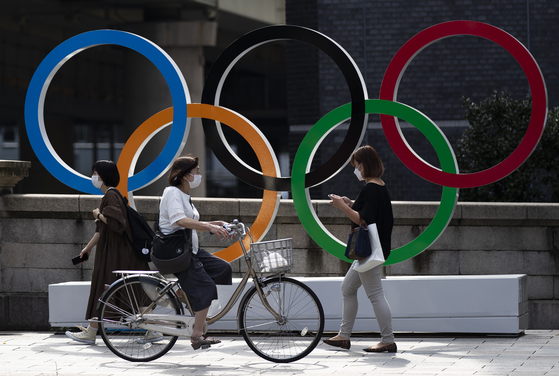 지난 15일 사람들이 일본 도쿄 니혼바시에 설지된 올림픽 조형물 앞을 지나가고 있다. 〈사진=AP 연합뉴스〉