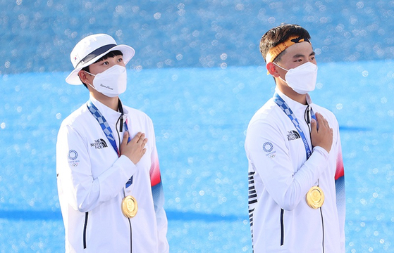 24일 일본 도쿄 유메노시마 공원 양궁장에서 열린 도쿄올림픽 양궁 혼성 결승전에서 금메달을 획득한 양궁 국가대표 안산(왼쪽)과 김제덕이 금메달을 목에 건 채 국기에 대한 경례를 하고 있다. 〈사진-연합뉴스〉