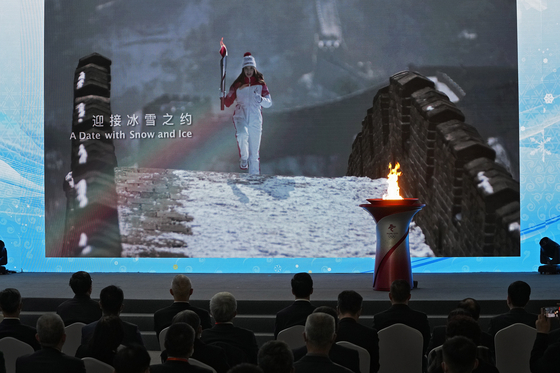 지난해 10월 베이징 동계올림픽 자원봉사자들이 성화 봉송 장면을 화면으로 관람하고 있다.〈사진=AP,연합뉴스〉