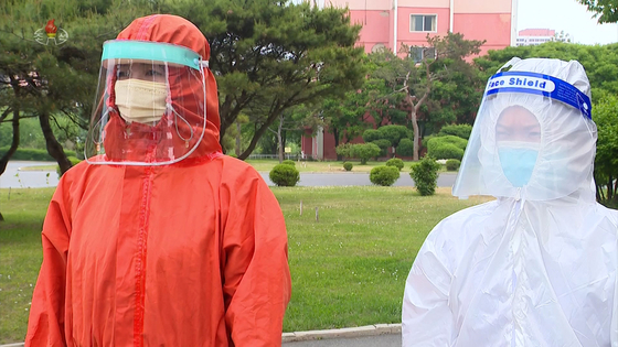 북한에 신종 코로나바이러스 감염증(코로나19) 확산세가 가파른 가운데 방역요원(오른쪽)이 영문으로 'Face Shield'(안면보호구)라고 적힌 안면보호구를 착용하고 있다. 〈사진=조선중앙통신·연합뉴스〉
