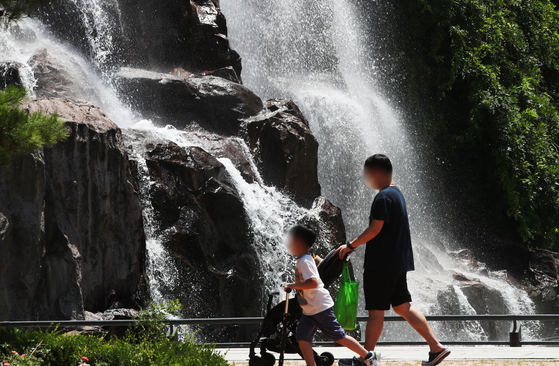 지난해 5월 25일 오후 서울 중랑구 용마폭포공원을 찾은 시민들이 떨어지는 물줄기를 바라보며 더위를 식히고 있다. 〈사진=연합뉴스〉