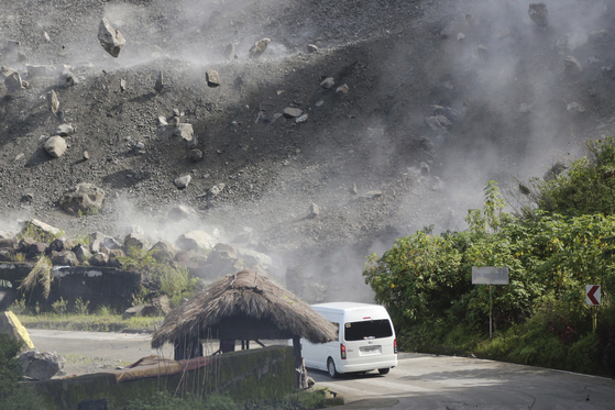 Boulders fall as a vehicle negotiates a road during an earthquake in Bauko, Mountain Province, Philippines on Wednesday July 27, 2022. A strong earthquake left some people dead and injured dozens in the northern Philippines on Wednesday, where the temblor set off small landslides and damaged buildings and churches and prompted terrified crowds and hospital patients in the capital to rush outdoors. One passenger was injured after a boulder hit the vehicle. (AP Photo/Harley Palangchao)    〈저작권자(c) 연합뉴스, 무단 전재-재배포 금지〉