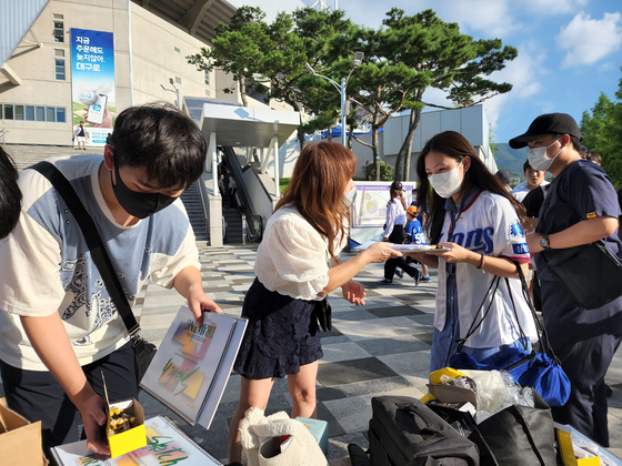 삼성팬들이 구단에 항의하기 위해 스케치북과 전자촛불을 나눠주고 있다〈사진=윤두열 기자〉