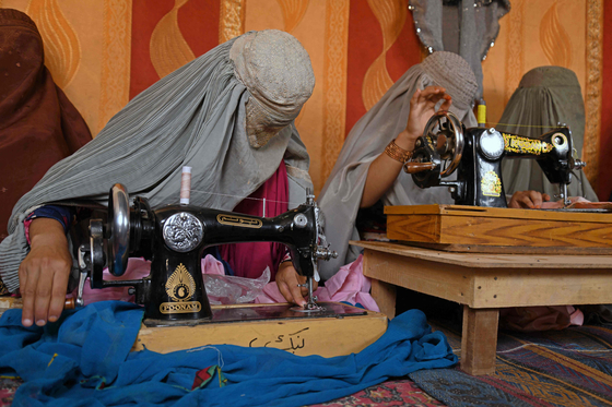 부르카를 입어 얼굴까지 가린 아프가니스탄 여성들이 재봉틀을 이용해 일을 하고 있다 〈출처=AFP 연합뉴스〉