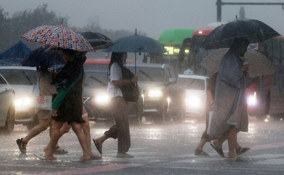 사람들이 우산을 쓰고 종종걸음으로 도로를 건너고 있다 〈사진-연합뉴스〉 