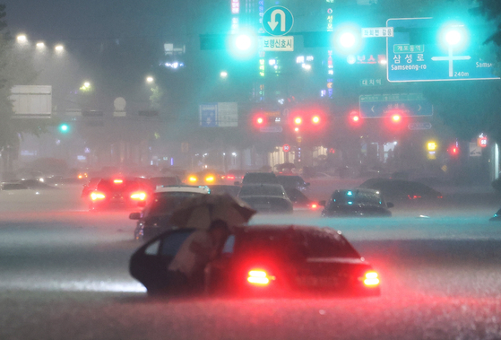 8일 밤 서울 강남구 대치역 인근 도로에서 차량이 침수되자 운전자가 대피하고 있다. 〈사진=연합뉴스〉