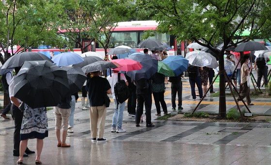 수도권 폭우가 계속된 지난 9일 오후 서울 종로구 세종로사거리 인근에서 퇴근길 시민들이 버스를 기다리고 있다. 〈사진=연합뉴스〉