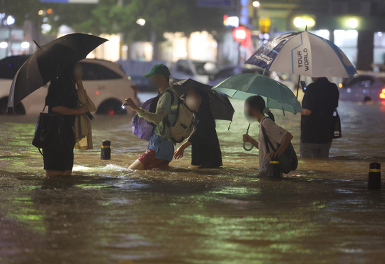 지난 8일 밤 서울 강남구 대치역 인근 도로와 인도가 물에 잠기면서 차량과 보행자들이 통행하는 데 불편을 겪고 있다. 〈사진=연합뉴스〉