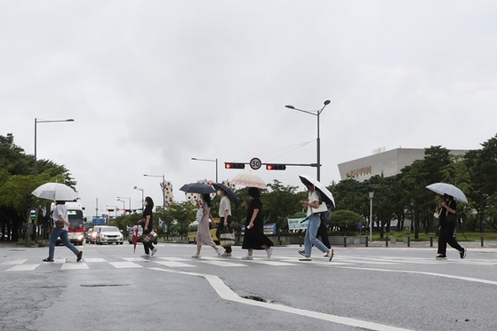 지난 16일 오전 광주 서구 치평동에서 시민들이 우산을 쓰고 걸어가는 모습. 〈사진-연합뉴스〉